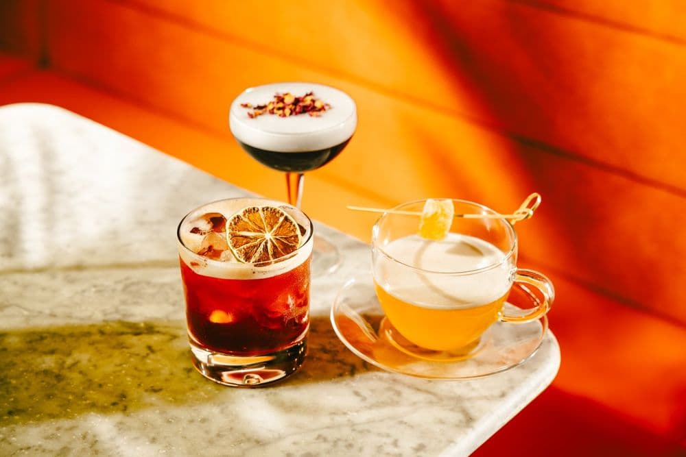 Two cocktails on a marble table in warm light