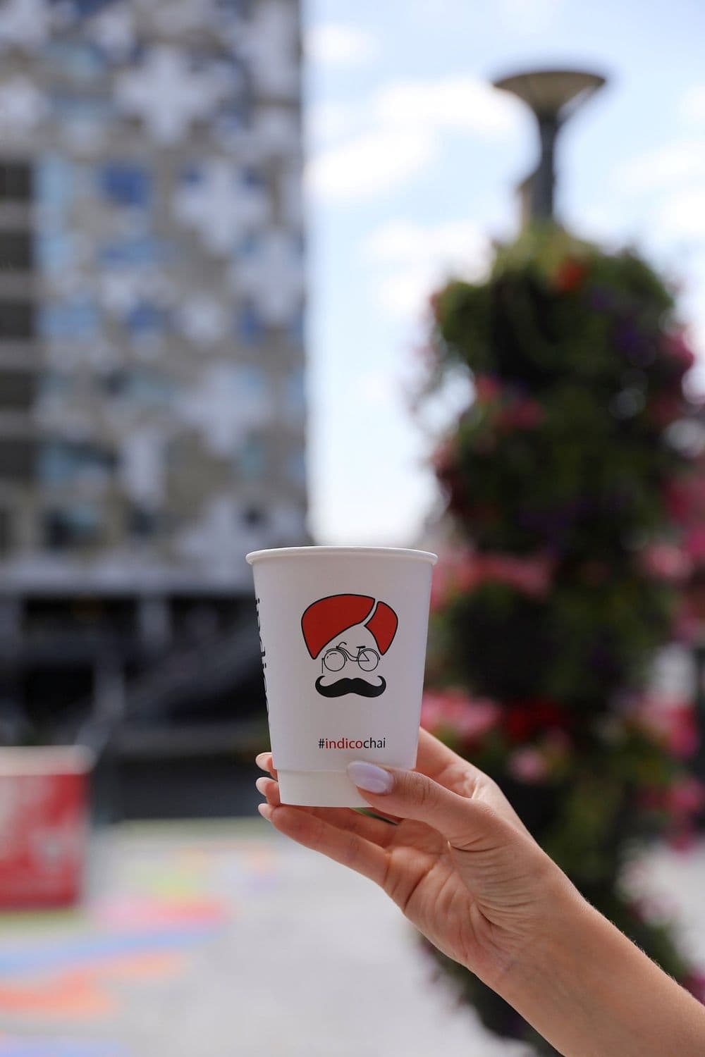 Indico takeaway cup held up outside the Mailbox