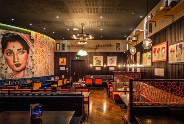 The dining room at Indico Mailbox with the Bollywood mural, leather booths and orange chairs